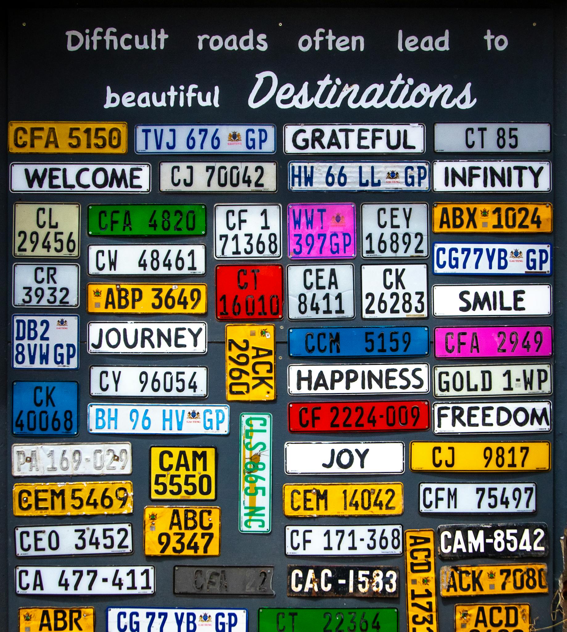 Collection of diverse license plates displaying motivational phrases on a vibrant background.